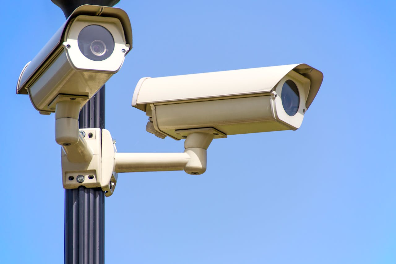 services-03 Outdoor security cameras mounted on a pole against a clear blue sky, ensuring vigilant surveillance.